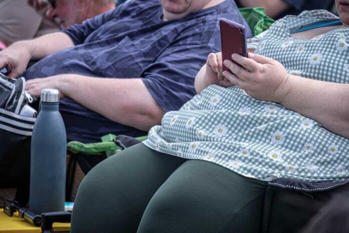 An,Obese,Man,And,Woman,Sitting,In,Chairs,And,Looking