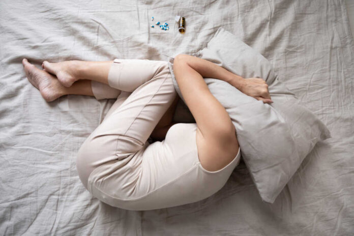 Depressed,Mature,Woman,Lying,In,Bed,With,Bottle,Of,Pills