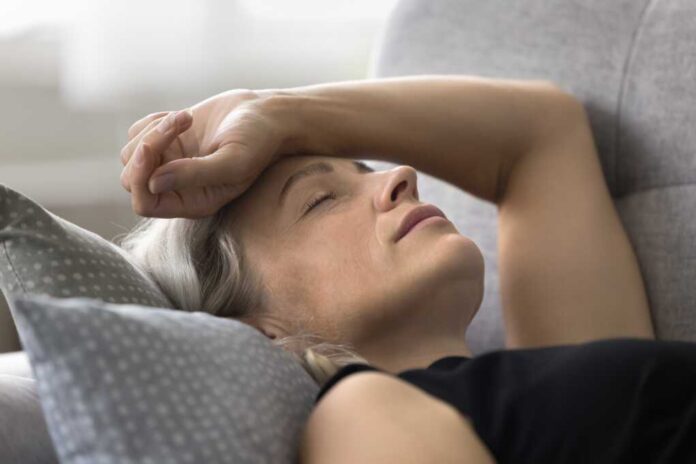 Weak,Senior,Woman,Lie,On,Sofa,Keep,Arm,On,Head