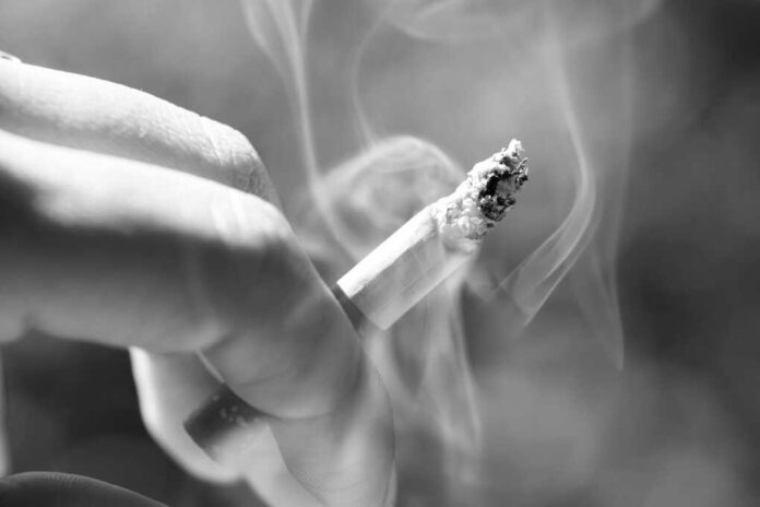 Woman,Smoking,A,Burning,Cigarette,With,Smoke,Between,Her,Fingers