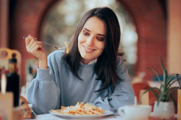 Woman,Eating,French,Fries,With,Cheese,In,A,Restaurant.,Girl