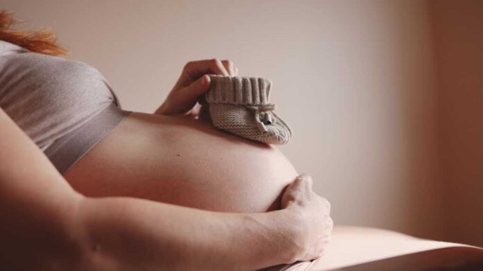 Happy,Pregnant,Woman.,Booties,Baby,Shoes,On,The,Belly,Of