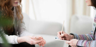 Two individuals engaged in a counseling session, one taking notes