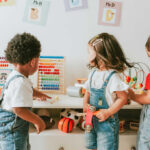 Three children engaged in play with educational toys in a colorful classroom