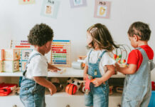 Three children engaged in play with educational toys in a colorful classroom