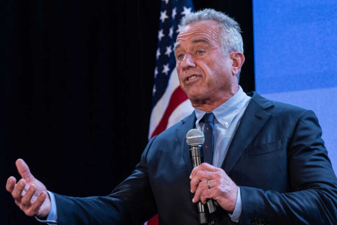 shutterstock2456684661jpg A man speaking into a microphone at a podium with an American flag in the background