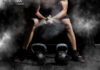 Athlete preparing to lift kettlebells in a gym with chalk dust in the air