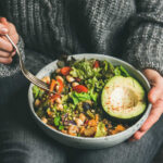 Unlock Fiber’s Full Potential with This Simple Trick A person holding a bowl of colorful salad with avocado and greens