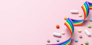 Colorful pills and a rainbow ribbon on a pink background