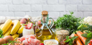 A variety of fresh foods including fruits, vegetables, and oils arranged on a table