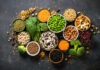 Unexpected Fiber Fix for Aging Skin An assortment of legumes, nuts, and fresh vegetables arranged in bowls on a dark surface
