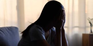 A silhouette of a person sitting with their head in their hands, conveying distress