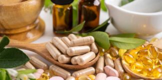 Various herbal supplements and vitamins arranged with leaves and a mortar