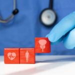 A doctor's gloved hand placing red blocks with health symbols on a table