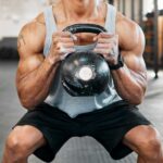 Athlete performing a kettlebell squat in a gym