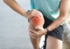 Athlete holding their knee in pain while exercising outdoors