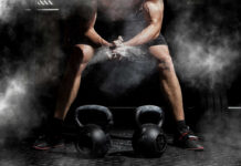 Athlete preparing to lift kettlebells in a gym with chalk dust in the air