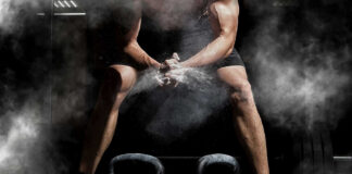 Athlete preparing to lift kettlebells in a gym with chalk dust in the air