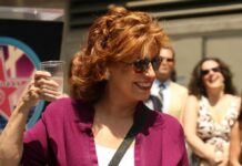 A woman holding a cup of water and smiling at an outdoor event