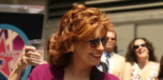 A woman holding a cup of water and smiling at an outdoor event