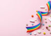 Colorful pills and a rainbow ribbon on a pink background
