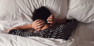 Child lying in bed with hands over ears