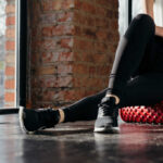 Yoga Poses That Melt Stress Fast Person using a foam roller for stretching in a fitness studio