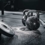 Kettlebells and weights on a gym floor with chalk dust