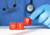 A doctor's gloved hand placing red blocks with health symbols on a table