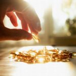 A hand reaching for a golden capsule among many on a table