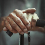 This Simple Test Predicts Aging Close-up of elderly hands resting on a walking cane
