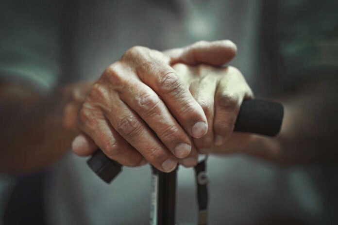 shutterstock1699580452jpg Close-up of elderly hands resting on a walking cane