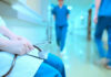 A healthcare professional holding a stethoscope in a hospital corridor