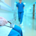 A healthcare professional holding a stethoscope in a hospital corridor
