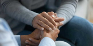 Two hands clasped together in a comforting gesture