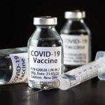 The Nocebo Side-Effect In The COVID-19 Pandemic Vials of COVID-19 vaccine and a syringe on a dark background