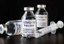 The Nocebo Side-Effect In The COVID-19 Pandemic Vials of COVID-19 vaccine and a syringe on a dark background