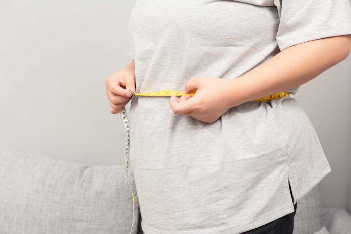 Person measuring their waist with a tape measure