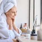 The 5-10 Shave Myth Woman in a bathrobe with a towel on her head, smiling at her reflection in a mirror