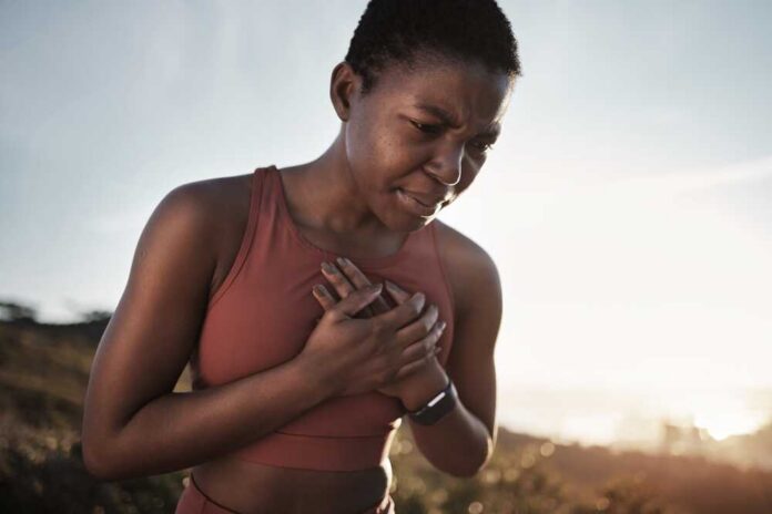 Black,Woman,,Runner,And,Heart,Attack,Pain,In,Nature,While A woman in athletic wear holding her chest with a pained expression outdoors