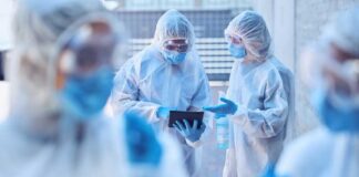 Healthcare professionals in protective gear discussing on a tablet