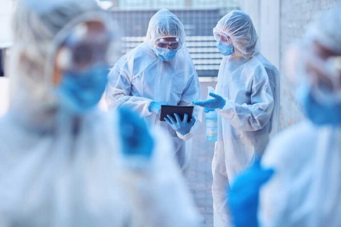 Healthcare professionals in protective gear discussing on a tablet