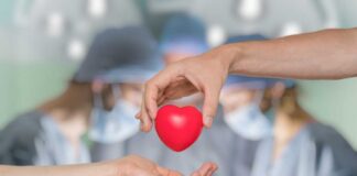 Two hands exchanging a red heart symbol in a surgical setting