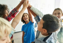 Group of children joyfully celebrating with high fives in a classroom