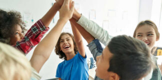 Group of children joyfully celebrating with high fives in a classroom