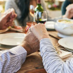 Salt Shocker Exposes Hidden Diet Divide Couple holding hands over a dining table with food and drinks