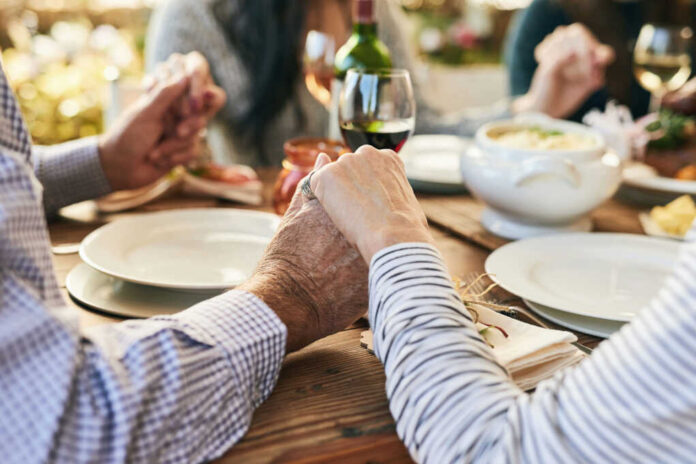 Couple holding hands over a dining table with food and drinks