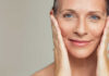 Close-up portrait of a smiling woman gently holding her face