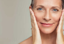 Close-up portrait of a smiling woman gently holding her face