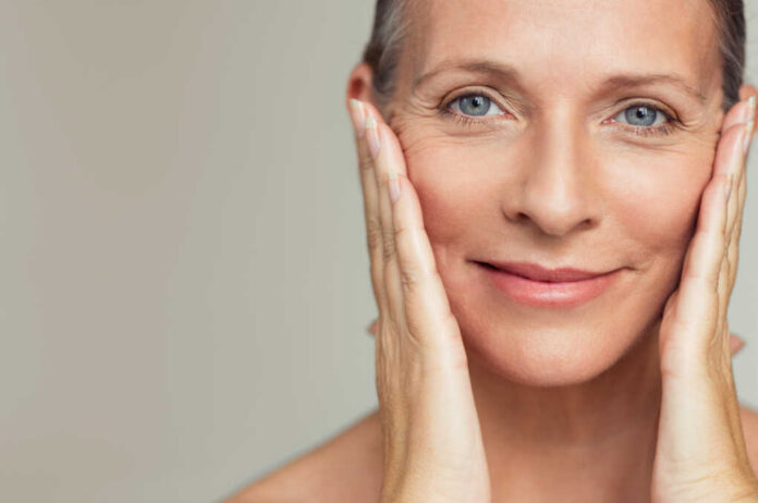 Close-up portrait of a smiling woman gently holding her face